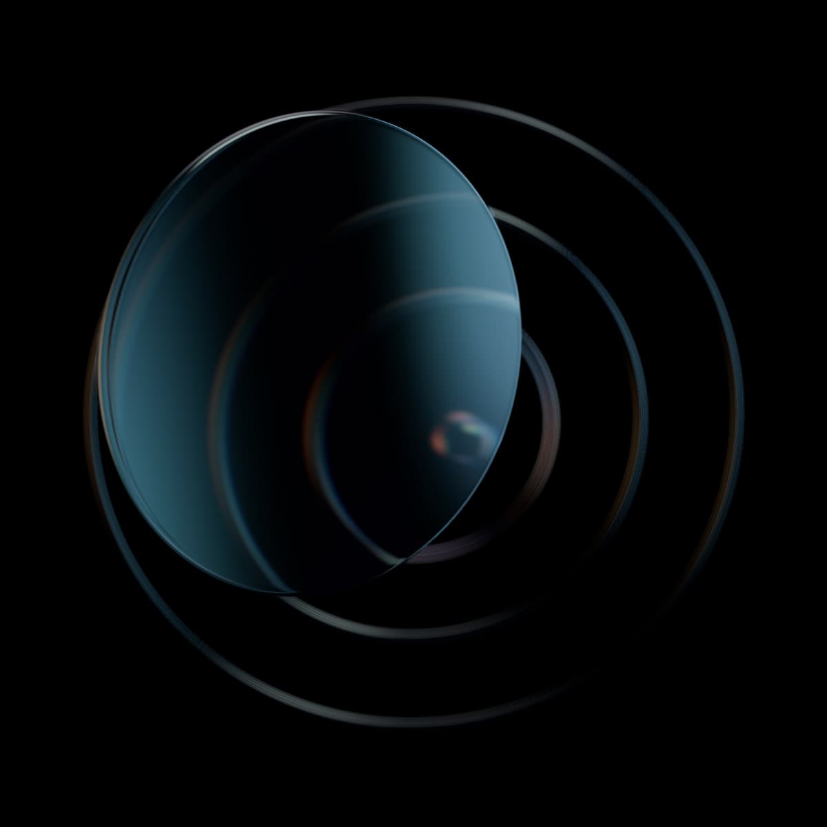 A clear biconvex glass lens in front of three thin concentric glass rings, the inner ones magnified through it.
