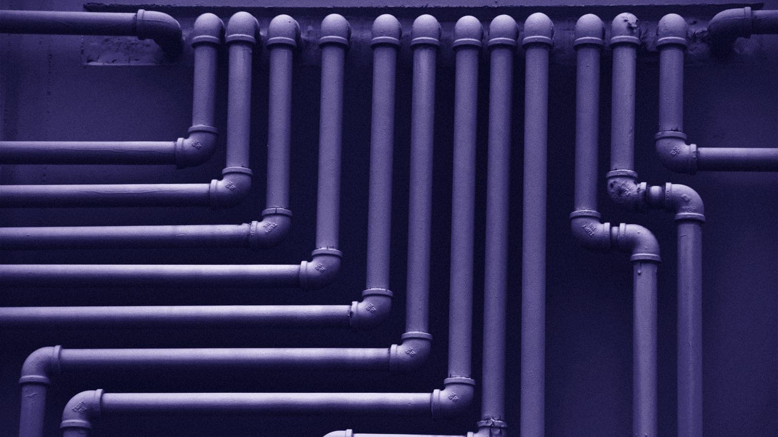 A wall of pale pipes running side by side, each turning down at a different point in a stepped pattern.
